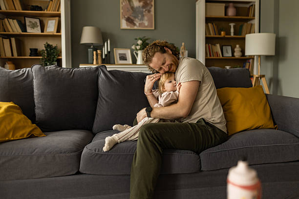 istock Father hugging baby daughter on sofa at home 2258578925
