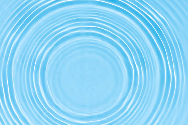 Bluewater waves on the surface ripples blurred. Defocus blurred transparent blue colored clear calm water surface texture with splash and bubbles. Water waves with shining pattern texture background.