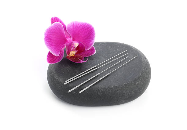Acupuncture needles, orchid flower and spa stone isolated on white