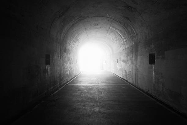 A concrete tunnel interior leading to bright daylight beyond.