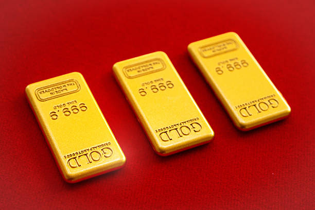 Three gold bars were arranged on a red velvet tray. Gold bars from the shop await customer purchase.