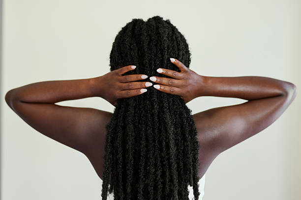 Horizontal back view of a woman with long black twists touching her hair.