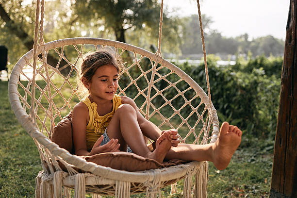 Young girl enjoying leisure time in a comfortable swing chair in a garden