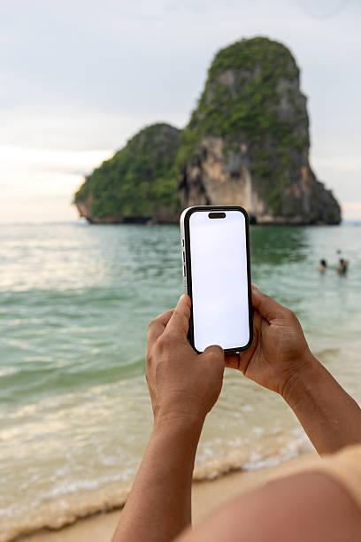 Person holding phone with white screen at Krabi beach