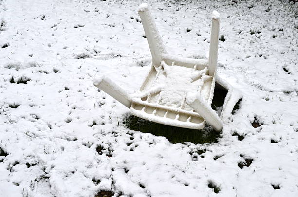 Snow-covered garden chair legs up in a domestic garden in Belgium