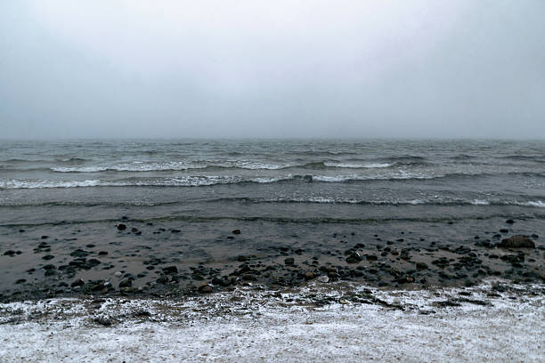 Cold winter weather on the Baltic sea coast in Sweden. Waves lapping on the frozen shore and the melting snow