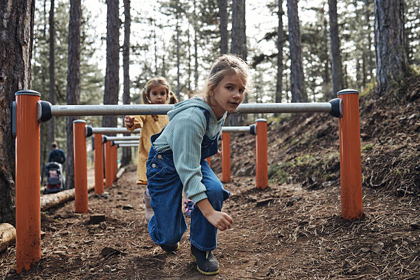 Two girls having fun jumping on an obstacle course in a forest