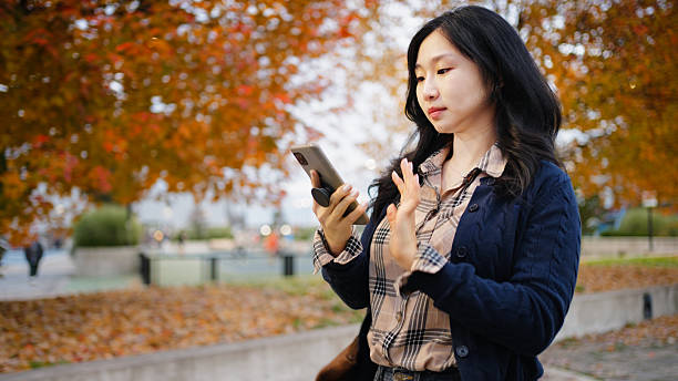 istock Asian woman using smartphone for video call outdoors 2258614489
