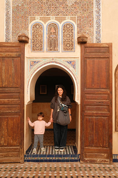 Mother and young child standing in an ornate doorway, exploring traditional Moroccan architecture and historical design elements