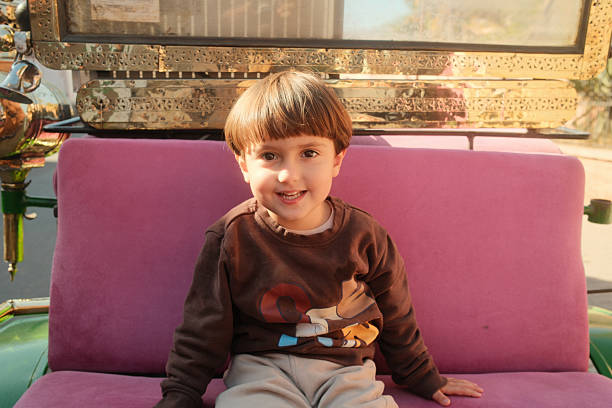 Happy preschool age boy smiling, sitting outdoors on a pink velvet seat in a traditional horse carriage in Marrakech, Morocco