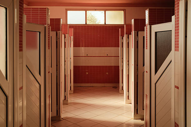 Empty Moroccan public restroom with white stalls and vivid red tile walls, symmetric interior, clean modern design and vanishing perspective
