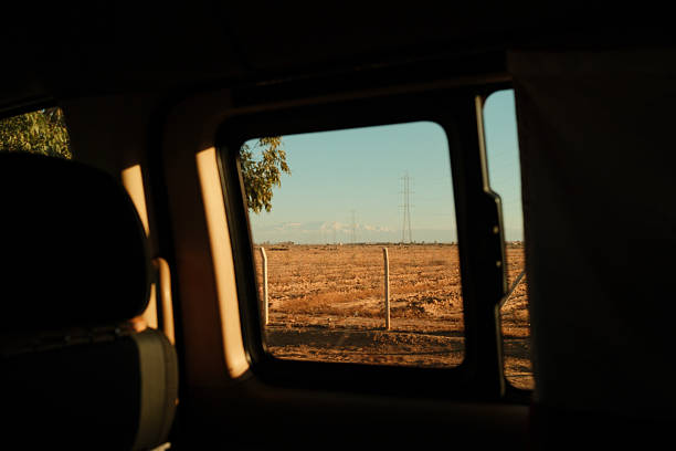 View from a car window on a road trip, showing arid Moroccan desert with a power line and mountains in the distance