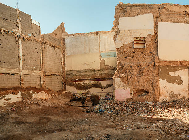 Demolished building interior in Morocco, showing textured walls, exposed brick, and a ground covered in construction debris under clear sky