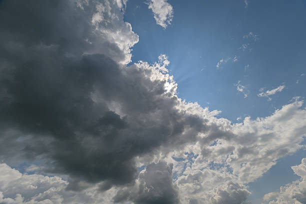 Witness an enchanting view of the clouds with sunlight beautifully peeking through, perfect for naturethemed projects