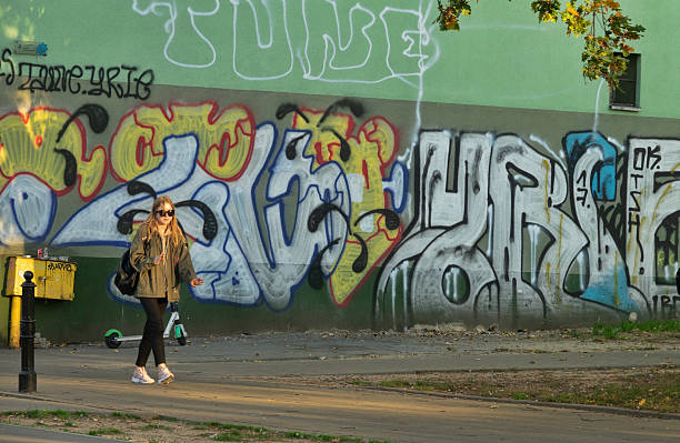 Warsaw, Poland - October 15, 2019: Passers-by on the background of a graffiti-covered wall