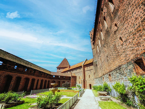 Long, dark brick tunnel narrowing towards a distant light source, creating a deep perspective