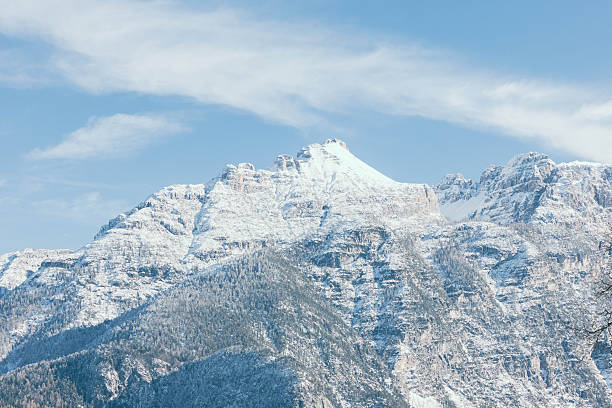 Snow-capped mountains of the Dolomites rise majestically against a blue sky