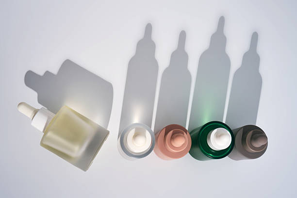 Skincare dropper bottles with natural cosmetic liquid creating elegant harsh shadows, top view product presentation