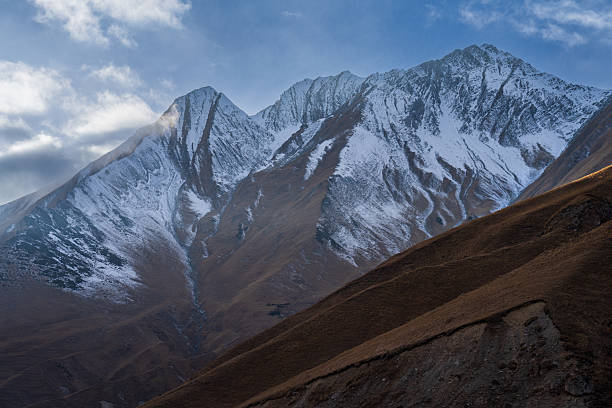 Snowy mountain peaks surrounded by cloudy highland atmosphere. Suitable for wilderness and environmental concepts.
