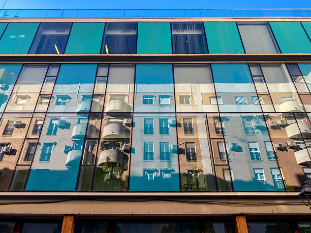 Low angle close-up view of a residential building reflection over the windows of another in front of it in the city of Valencia, Spain