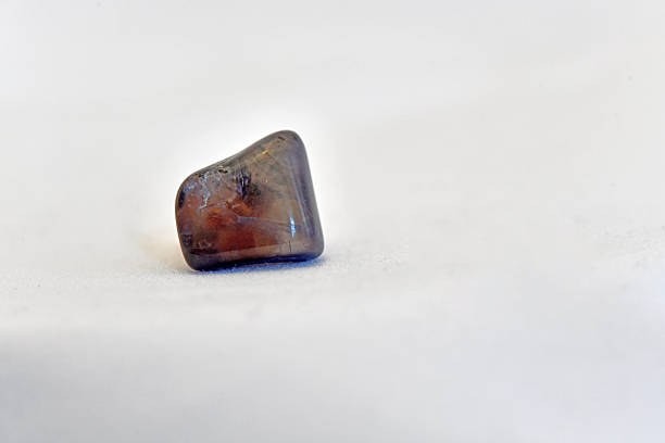 A detailed macro shot of a polished, dark translucent cardiolite mineral specimen with subtle internal textures, isolated on a clean white background.