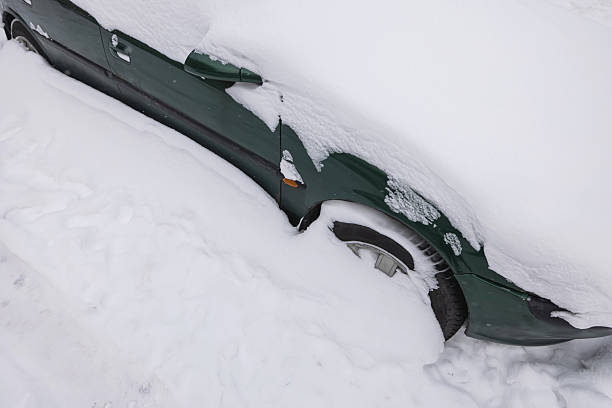 An abandoned vintage coupe buried in snow.