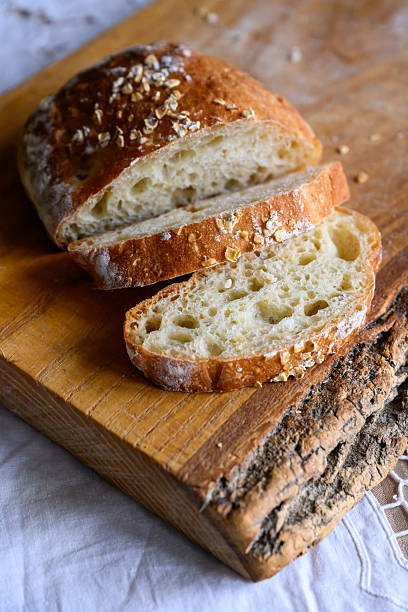 The airy textured whole wheat ciabatta bread on rustic oak cutting board