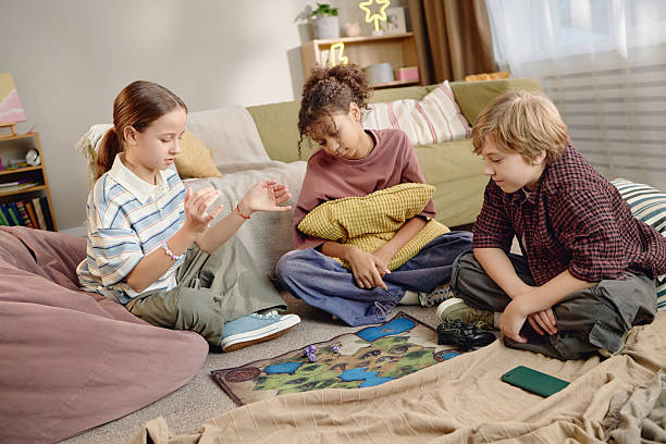 Lisbon, Portugal, August 31, 2025, Kid holding dice while playing monopoly board game, with money and cards visible on the table