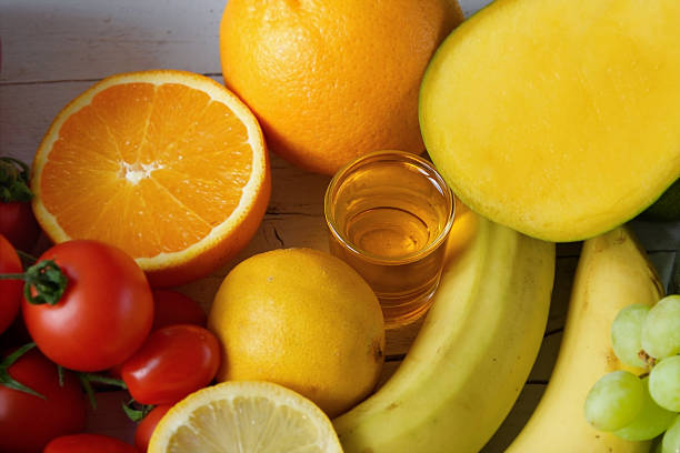 Close-up overhead composition of fresh fruit including oranges, bananas, mango, tomatoes, grapes and olive oil. The colorful arrangement highlights natural sweetness, vitamins, and everyday healthy eating. Bright, appetizing scene with copy space suitable for healthcare, nutrition, or wellness communication.