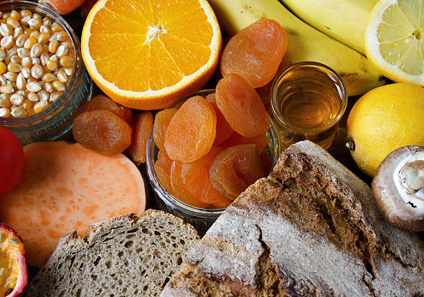 Close-up of natural snack foods including dried fruit, citrus, whole grain bread, honey, and fresh produce arranged on a rustic wooden surface. This image conveys mindful nutrition, energy, and wholesome eating.