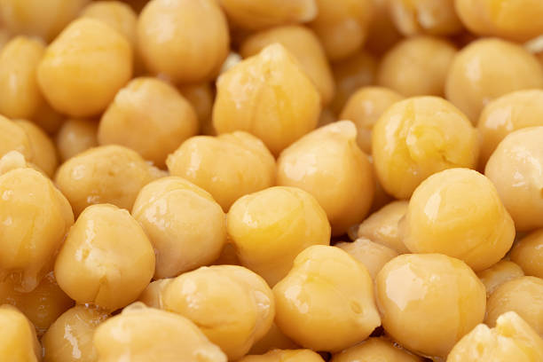 Soaked chickpeas textured background, chick pea in water closeup, swollen wet Cicer arietinum fruits, macro raw Bengal gram legume preparation, garbanzo beans pattern, Egyptian pea seeds