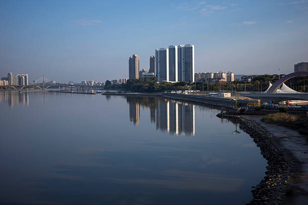 Urban skyline with high-rise buildings reflecting on calm water, serene atmosphere, potential for real estate or travel promotion.