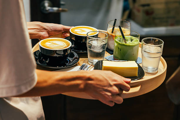 Unrecognizable waiter is serving coffee and dessert with tray at coffee shop.