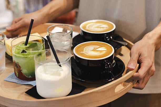 Unrecognizable waiter is serving coffee and dessert with tray at coffee shop.