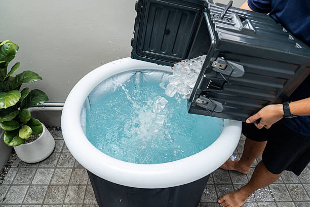 Pouring ice cubes into inflatable tub for ice bathing, practicing cold therapy and Wim Hof Method for wellness meditation fitness recovery and sports therapy.