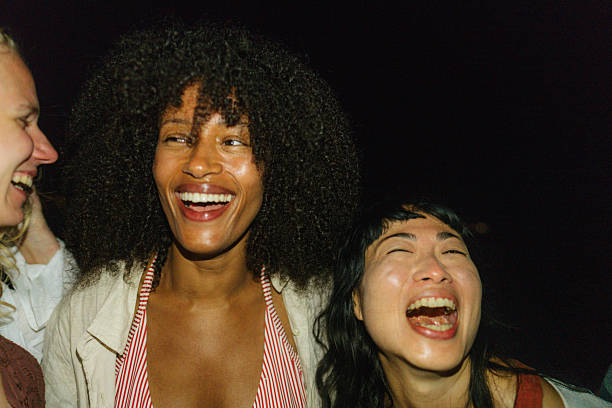 Photo of a diverse group of female friends joyfully hanging out together at the local beach, laughing and sharing stories in a vibrant atmosphere.