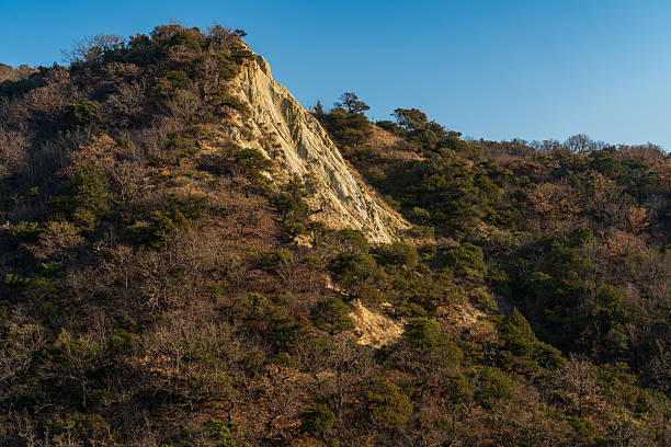 Light-colored rock outcrop contrasting with dry mountain slopes in arid landscape. Suitable for geology and natural background use.