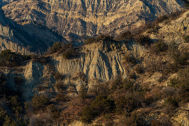 Textured rock formations and eroded slopes in dry mountain landscape. Suitable for geology, environment, and background use.