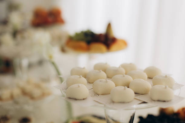 Bride and groom cutting into a white floral wedding cake. Represents tradition, joy, and the shared moments of a wedding reception.