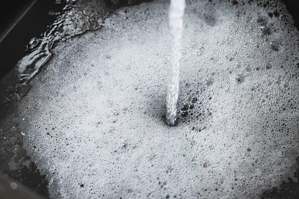 Water flowing into kitchen sink. Water with foam