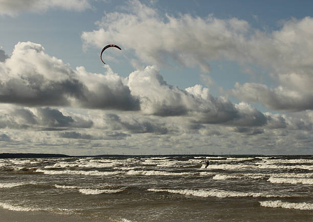 Dramatic cloudy sky, strong wind and rough water create a sense of freedom, motion and extreme outdoor sport. Photo taken on the coast of Tallinn, Estonia, in 2023. Concept of active lifestyle, travel, adventure, nature and wind power.