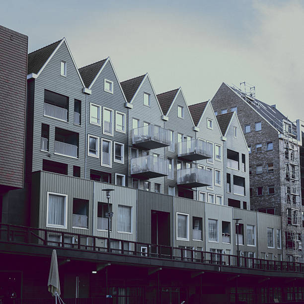 A contemporary architectural scene in the Netherlands featuring modern apartment buildings inspired by traditional Dutch gabled houses. Clean lines, pastel facades, geometric balconies, and reflections on calm water create a minimalist urban landscape with a strong sense of symmetry and design.