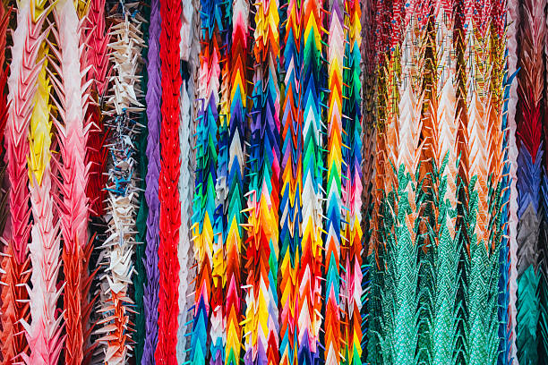 Rows of colorful origami paper cranes hanging together as a vibrant cultural display in Japan. Traditional Japanese origami symbolizing peace, hope, wishes, and remembrance. Bright abstract composition ideal for concepts of creativity, culture, celebration, and diversity.