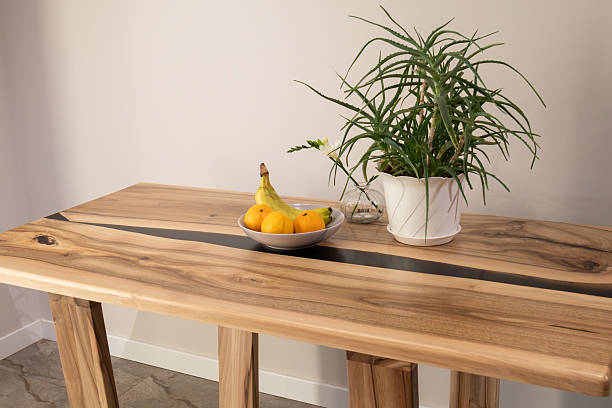 Fresh fruits in a bowl rest atop a striking wooden table, accompanied by a lush green plant, creating a warm, inviting atmosphere indoors