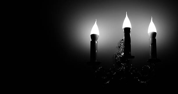 Vintage Style Wall Lamp in Three Candles Form Illuminate a Wall Black and White Stock Photo