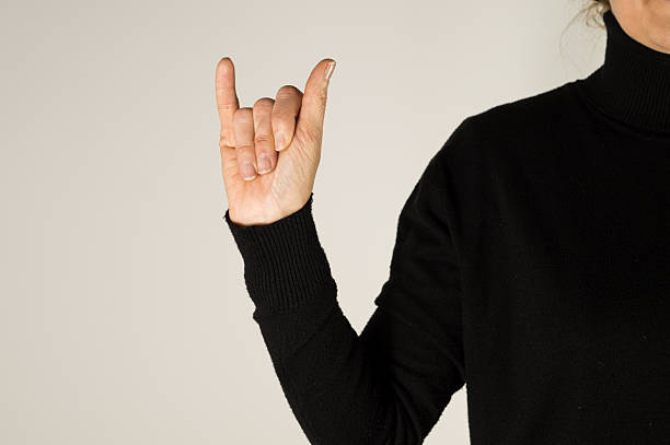 A close-up of a person's hand showing the letter Y in ASL, with the thumb and pinky extended and middle fingers folded