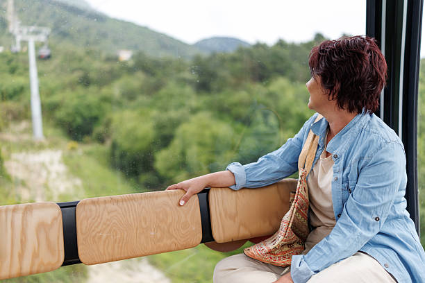 Happy mature woman enjoying scenic view from cable car