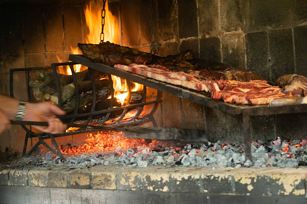 The grill chef places hot charcoal under the meat.