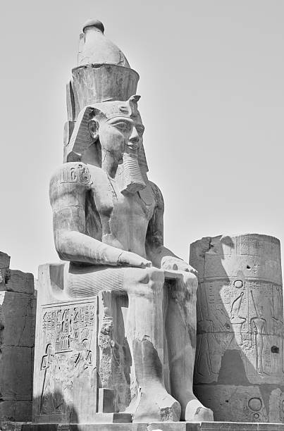 A large statue of an Egyptian Pharaoh seated majestically, surrounded by ancient hieroglyphs. The intricate carvings and art depict historical elements from ancient Egypt. Perfectly preserved archaeological monument.