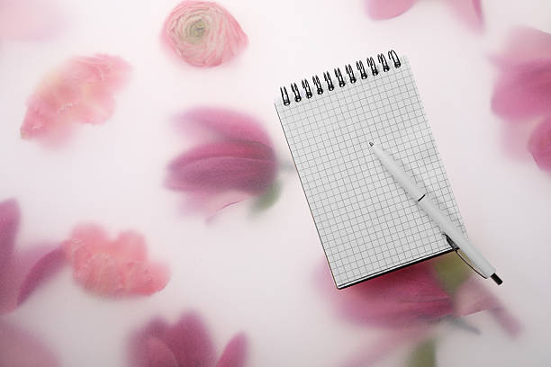 Guest list. Notebook and pen on spring floral background, flat lay. Space for text